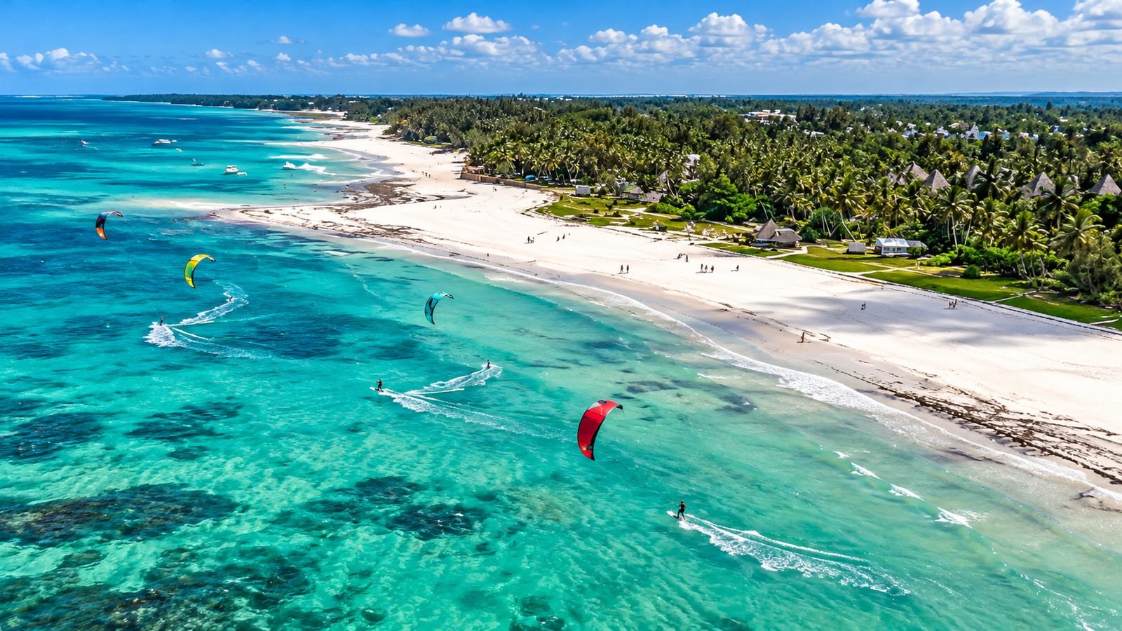 Vista dall'alto di Diani Beach: sabbia bianca, palme e kitesurf sul mare turchese