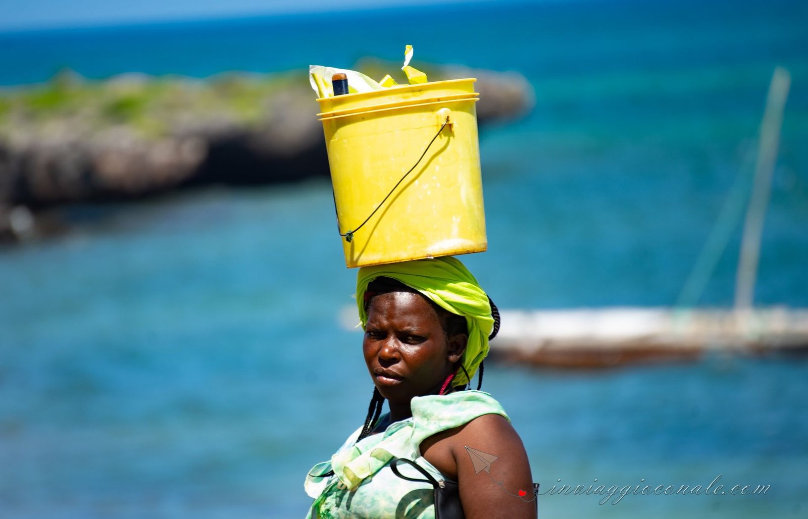 Donna con un secchio in equilibrio sulla testa al mercato del pesce, Kenya