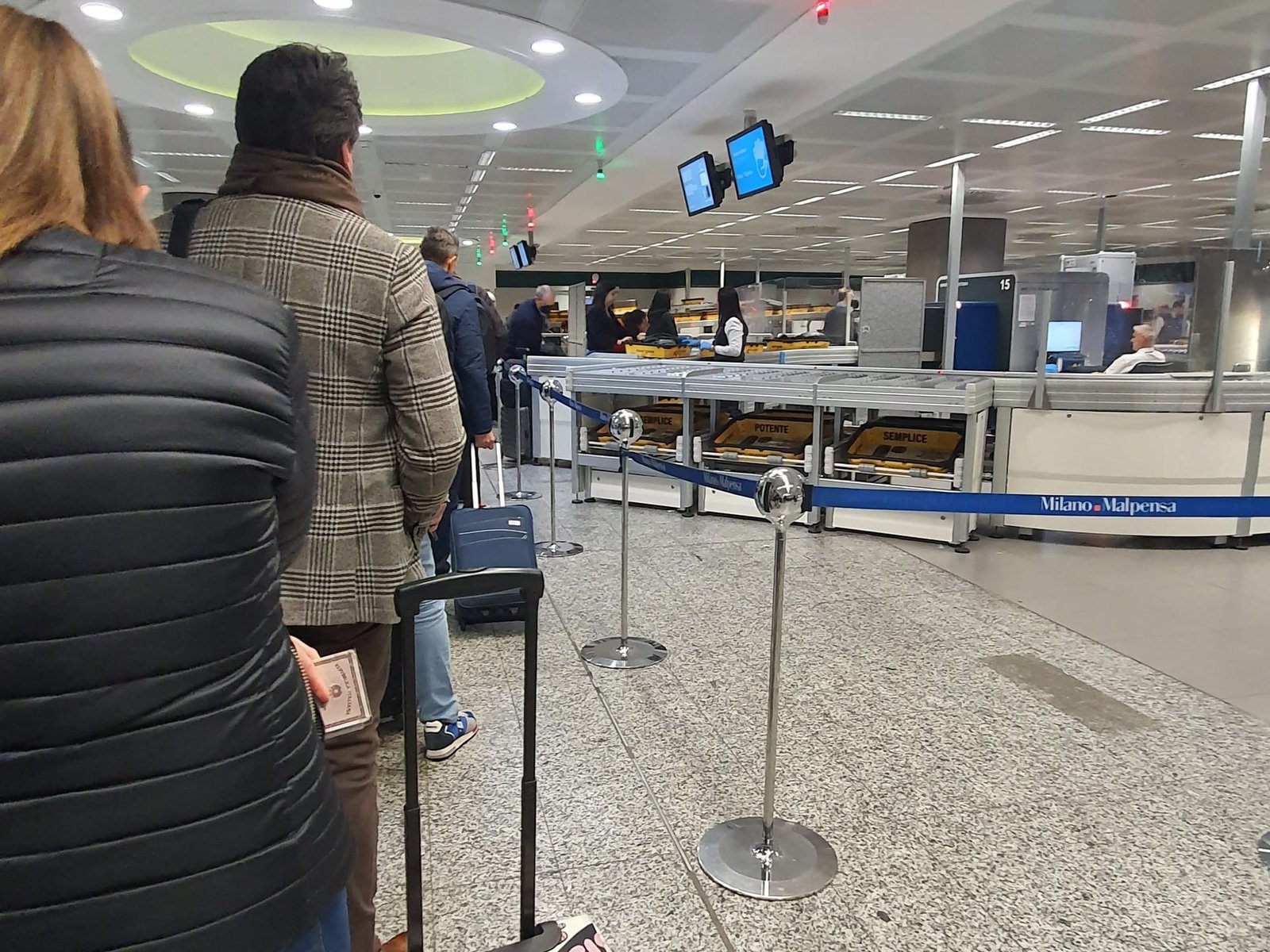 Passeggeri in fila con i trolley ai banchi dell’aeroporto di Milano Malpensa