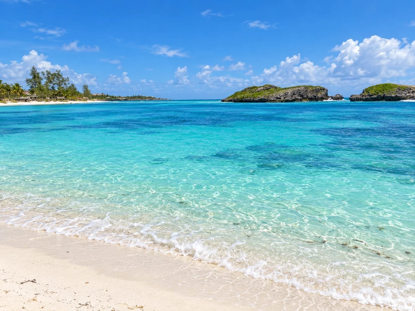 Laguna turchese con l'acqua bassa, la spiaggia con le palme e gli isolotti di roccia