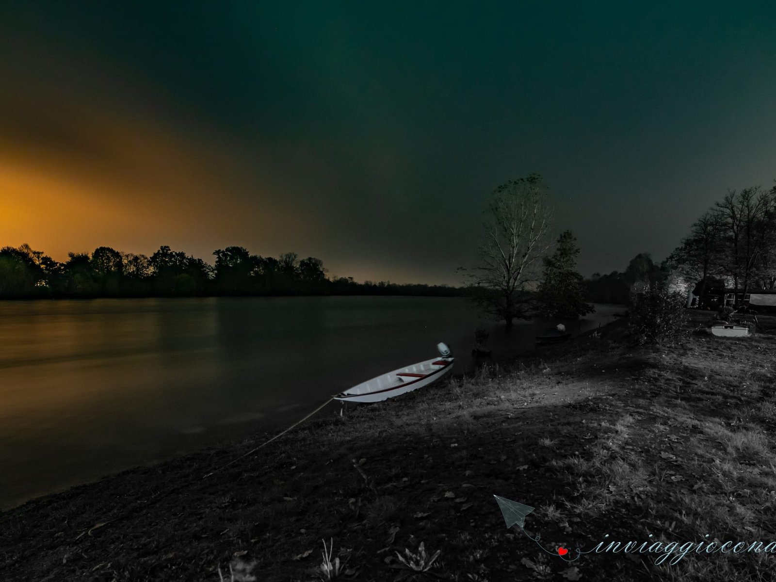 La riva di un lago di notte, con una barca a remi tirata a secco