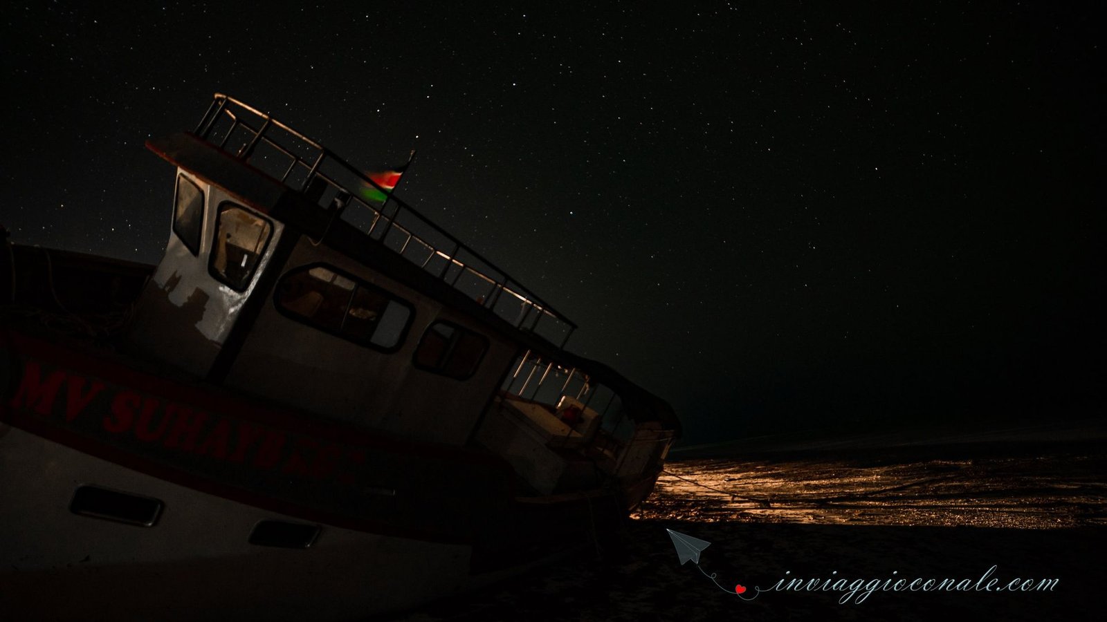 La barca arenata fotografata di notte, sotto le stelle